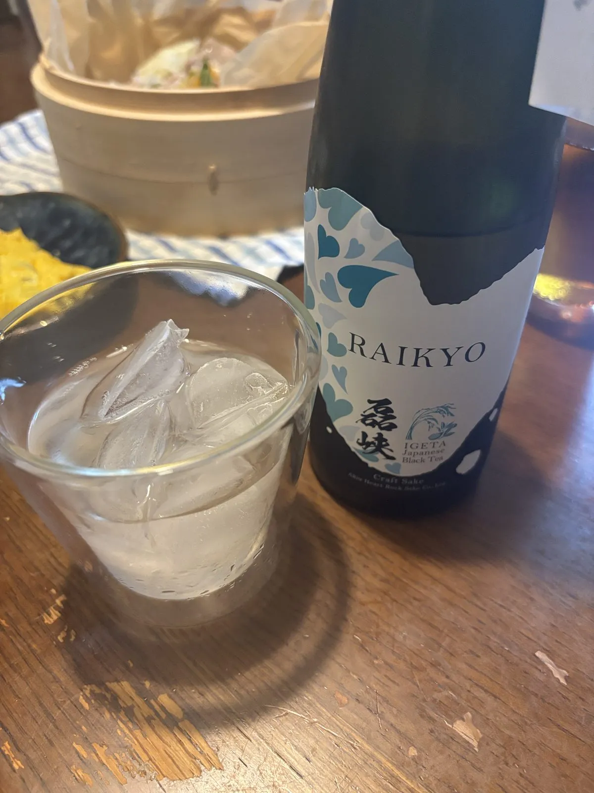 磊峡 和紅茶のオンザロック。氷を入れたグラスとボトル、奥にせいろの晩ごはん